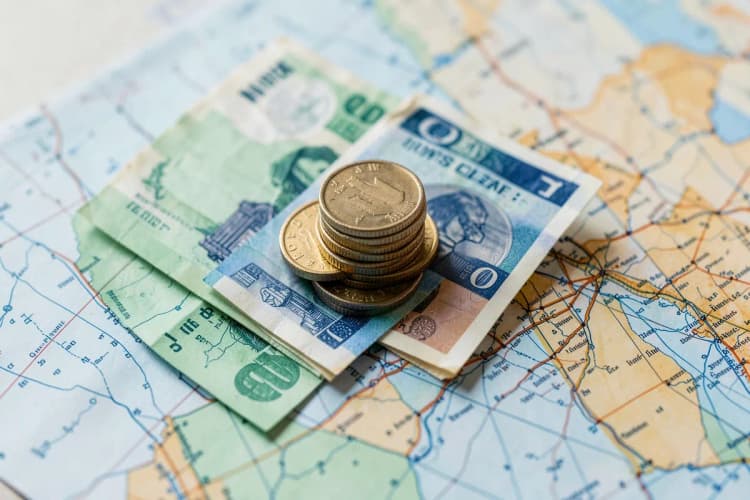 Uma pilha de moedas e notas de dinheiro em cima de um mapa.